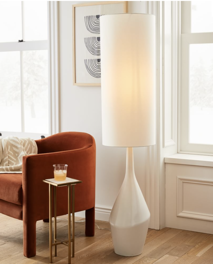 What furniture sells best image: White floor lamp next to red velvet chair in living room